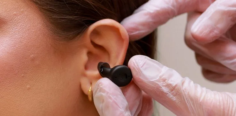 Profissional encaixando aparelho auditivo discreto no ouvido